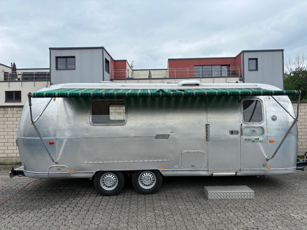 Airstream in Silber, seitlich von Außen mit ausgefahrener Markise